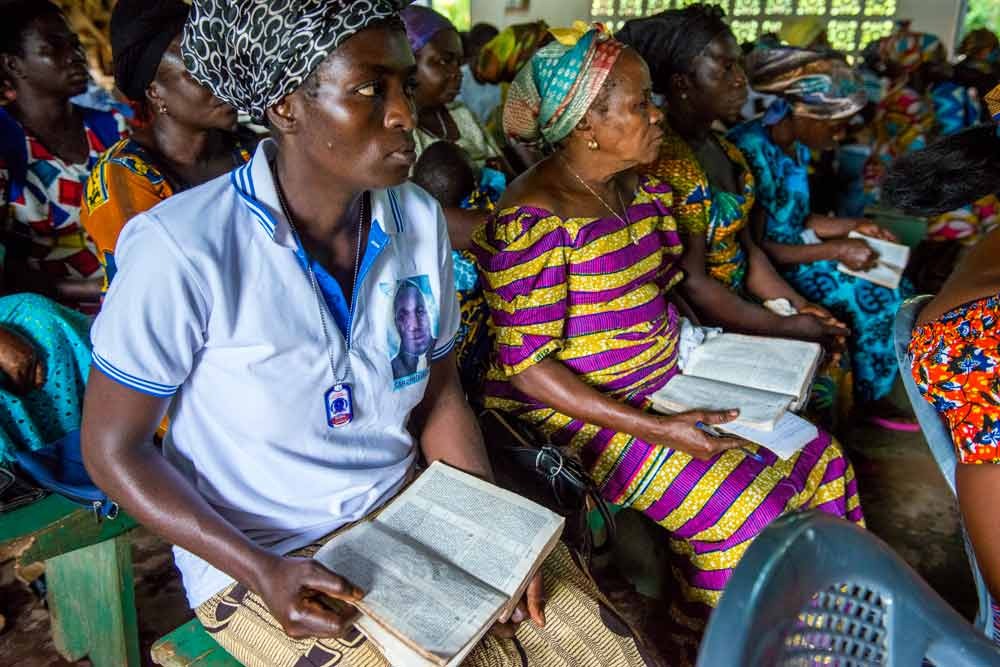 Women hold their open Siwu New Testaments attentively in a church service.