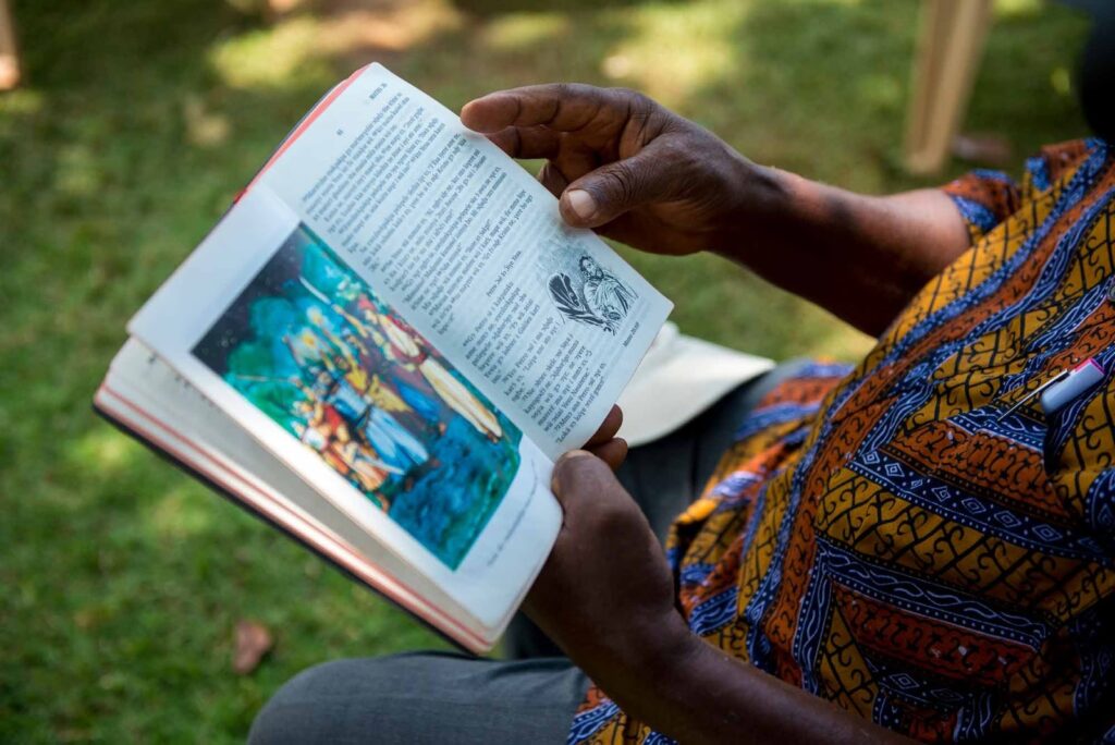 Isaac holds his open Siwu New Testament.
