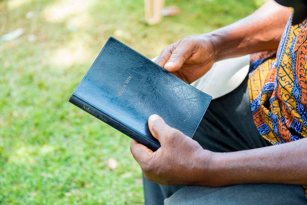 Man hold the printed Siwu New Testament.