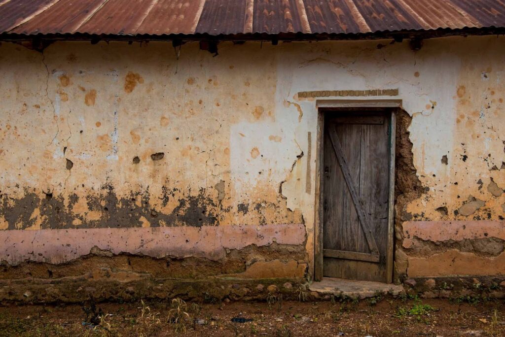 Text written above a village house door that says "Do good to your enemies."