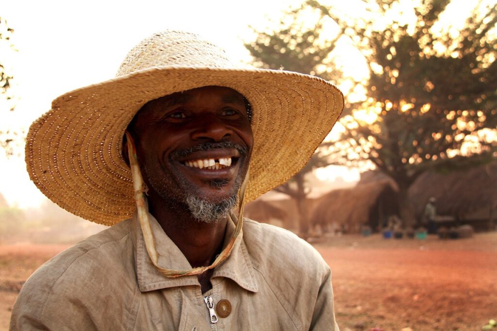 Man from Cameroon smiling with a straw hat on.