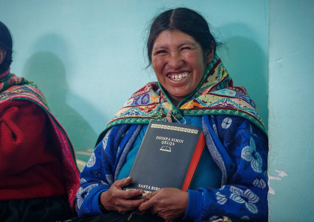 A woman smiles as she poses with the Quechua Bible she has just received during a literacy class in Peru.