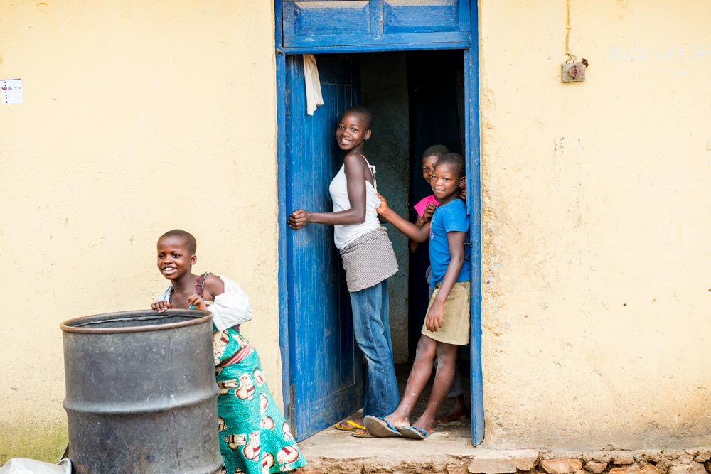 teenage girl stands in a doorway with some other kids