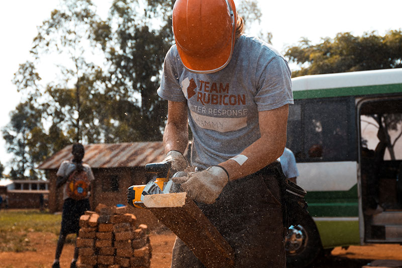 volunteer building using a saw on wood