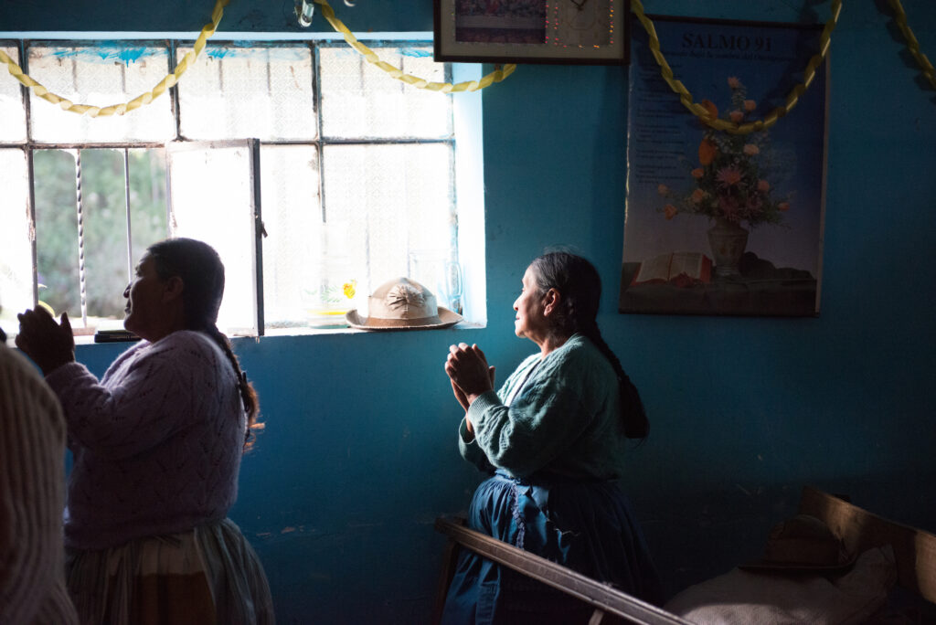 An older near a window prays.