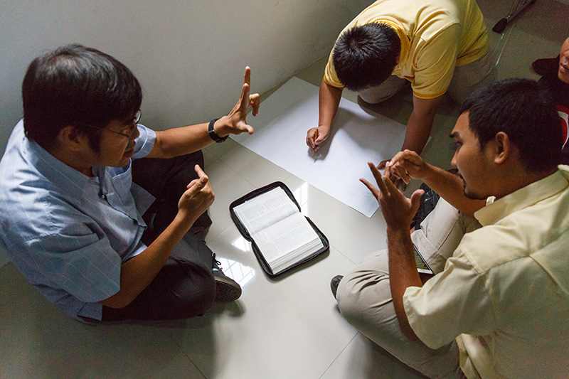 Three men gathering for a sign language bible study.