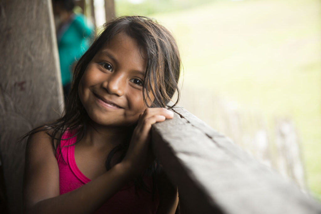 A girl smiling and resting her head on a railing