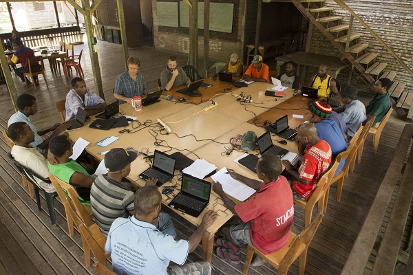 A group of men working around a table together, discussing the translation for their individual language communities