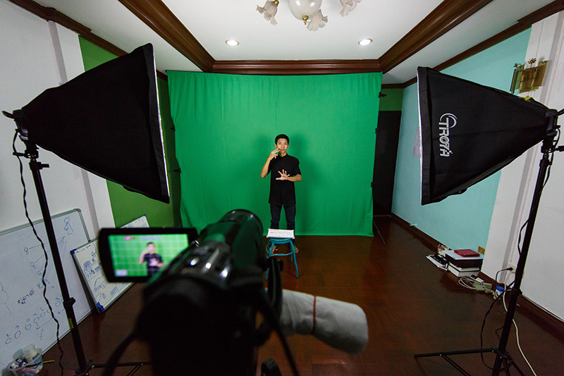 man signing in front of green screen for video camera