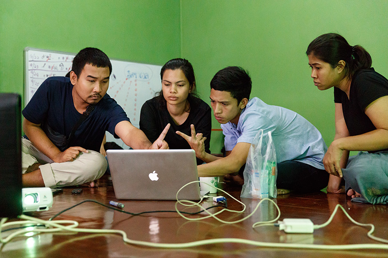 Tum working with colleagues, looking at laptop