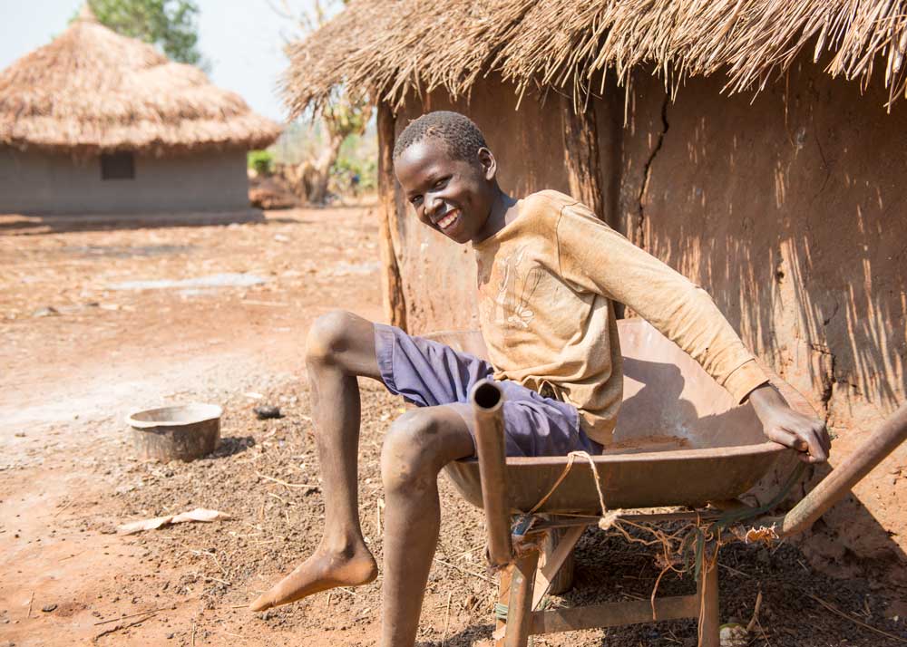Smiling boy sitting in a wheelbarrow