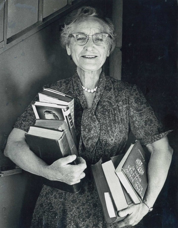 Faye Edgerton, Wycliffe linguist, smiling and holding many books.