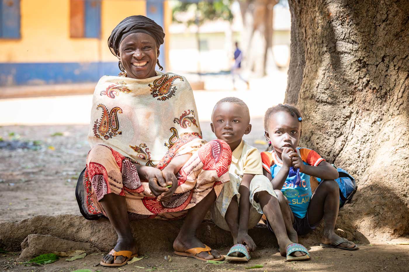 Woman with children seated under a large tree