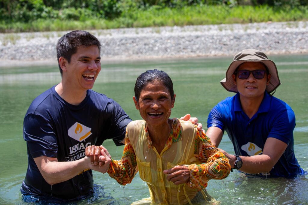 Isnag woman being baptized in a river.