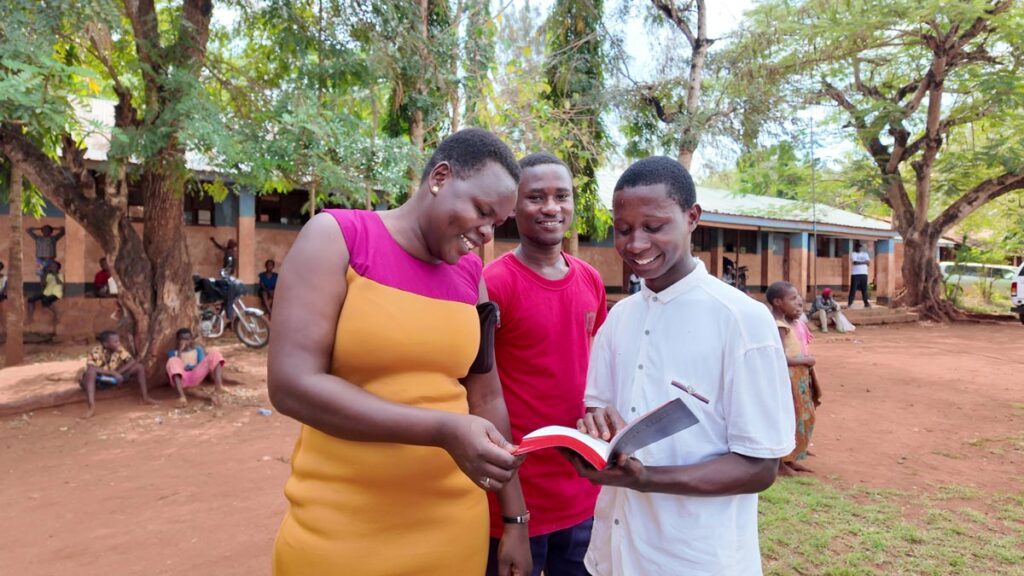 Three people reading their new Scripture.