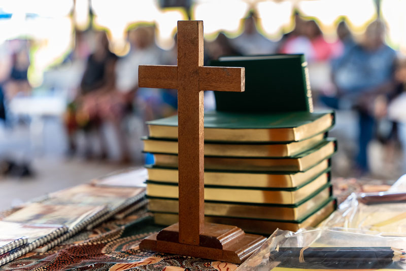 /></figure>
<p>Check out the <a href= Wooden cross standing on a table in front of a stack of new Bibles