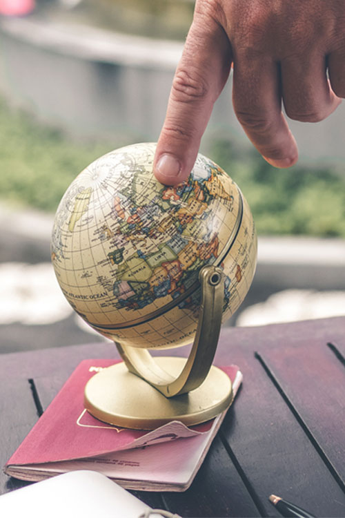 man pointing to small globe on an outside table