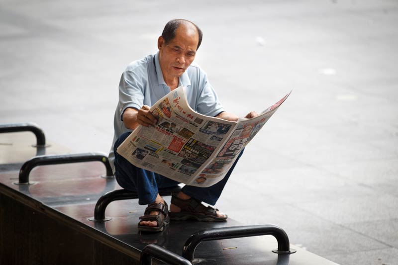 Man sitting and reading a newspaper.
