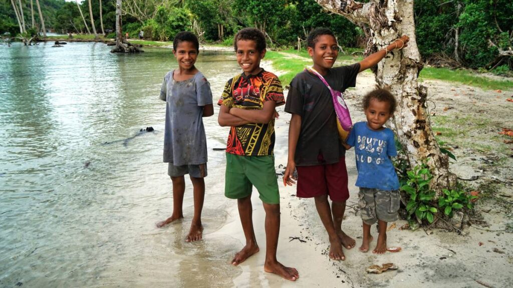Four boys standing on the beach in Papua New Guinea.