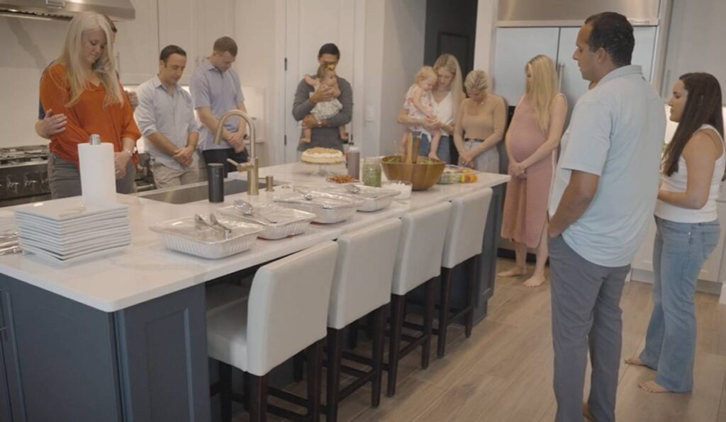Individuals participating in a giving circle, praying over their meal.