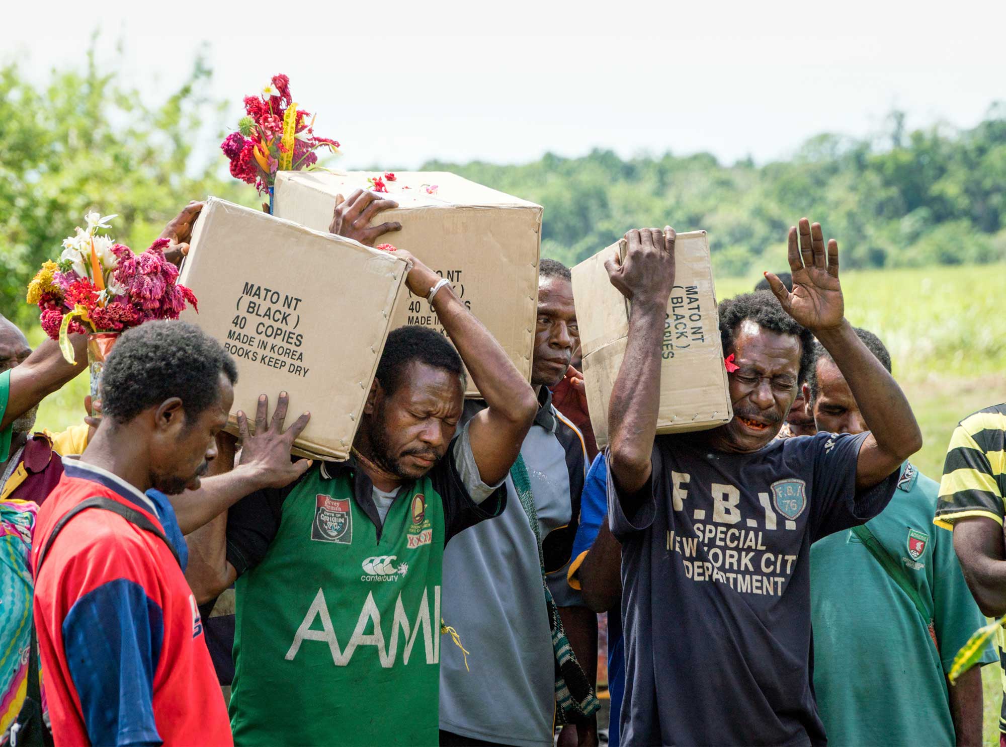 Pacific men carrying boxes of New Testaments