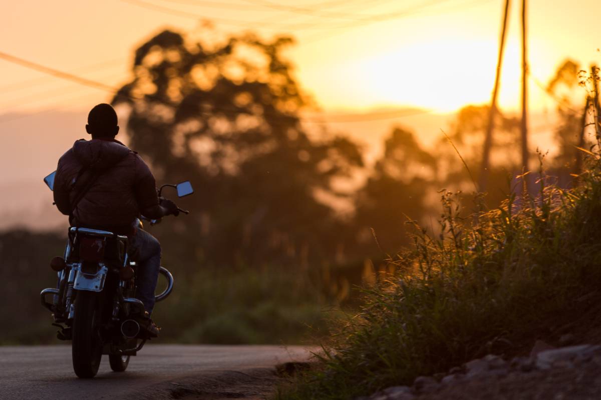 Person riding motorcycle with sunset in the background.